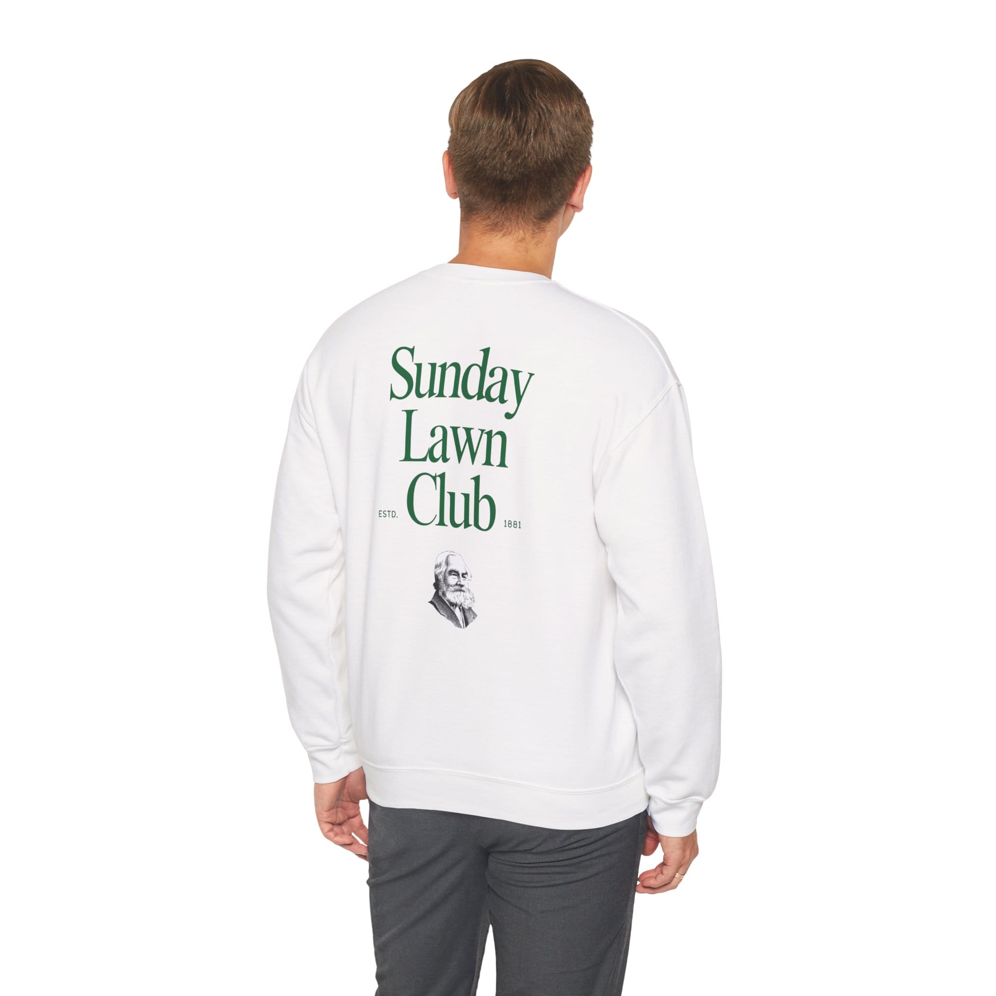 A person faces away, wearing the Sunday Lawn Club Heavy Blend™ Crewneck Sweatshirt featuring green "Sunday Lawn Club" text and a small man's face illustration on the back.