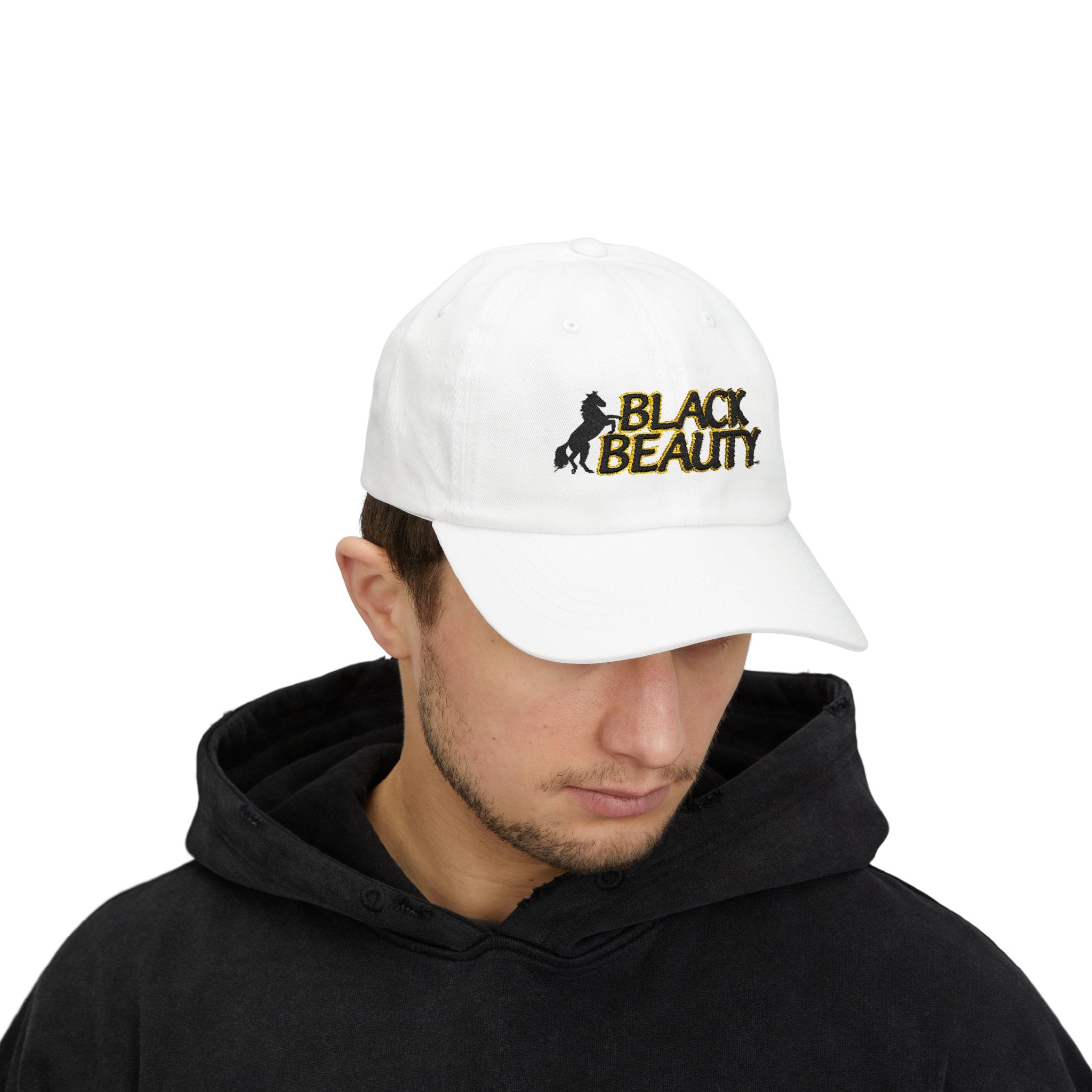 A person wears the Black Beauty Embroidered Dad Cap, featuring "Black Beauty" and a horse logo on the front, paired with a black hoodie and looking down.