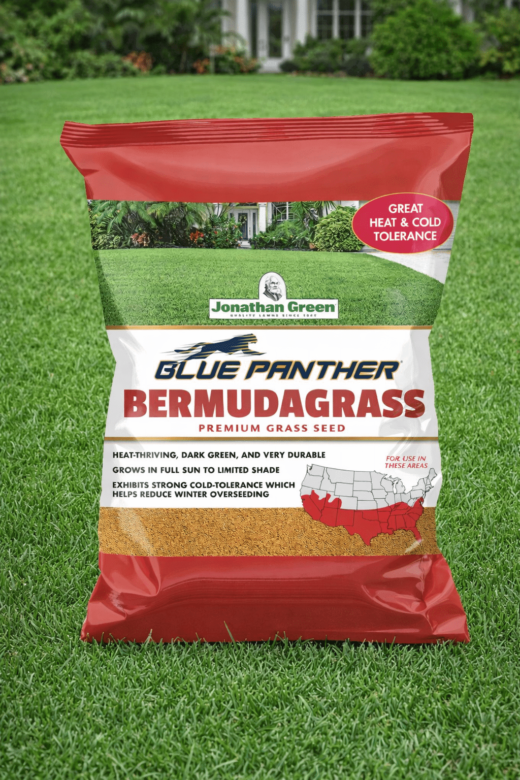 A bag of Blue Panther® Bermuda Grass Seed stands upright on a lush lawn, with a house visible in the background.